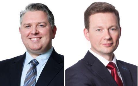 Two professional headshots of men wearing dark business suits against a white background. One man is wearing a light blue shirt with a patterned tie, and the other is wearing a white shirt with a red tie.