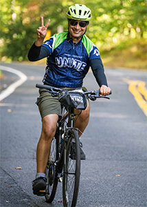 Dr. Dash gives a peace sign while riding a bike during BellRinger