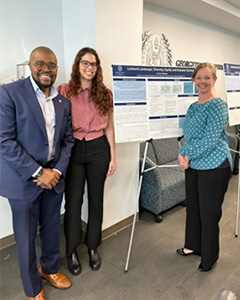 Dr. King, Lauren and Dr. Graves stand in front of a poster