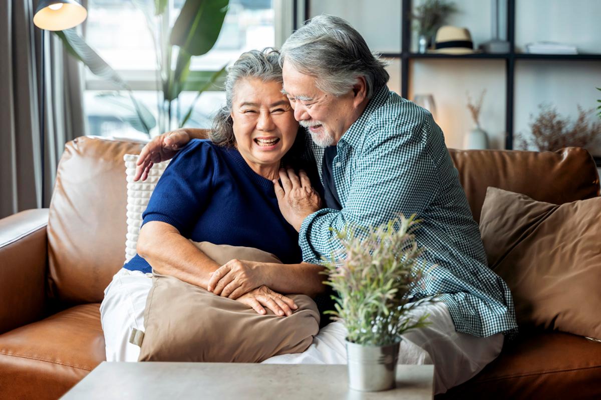 Happy Older Asian Couple sitting on a couch