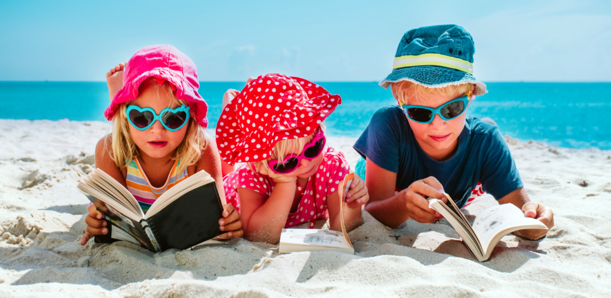 Young kids reading books on the beach