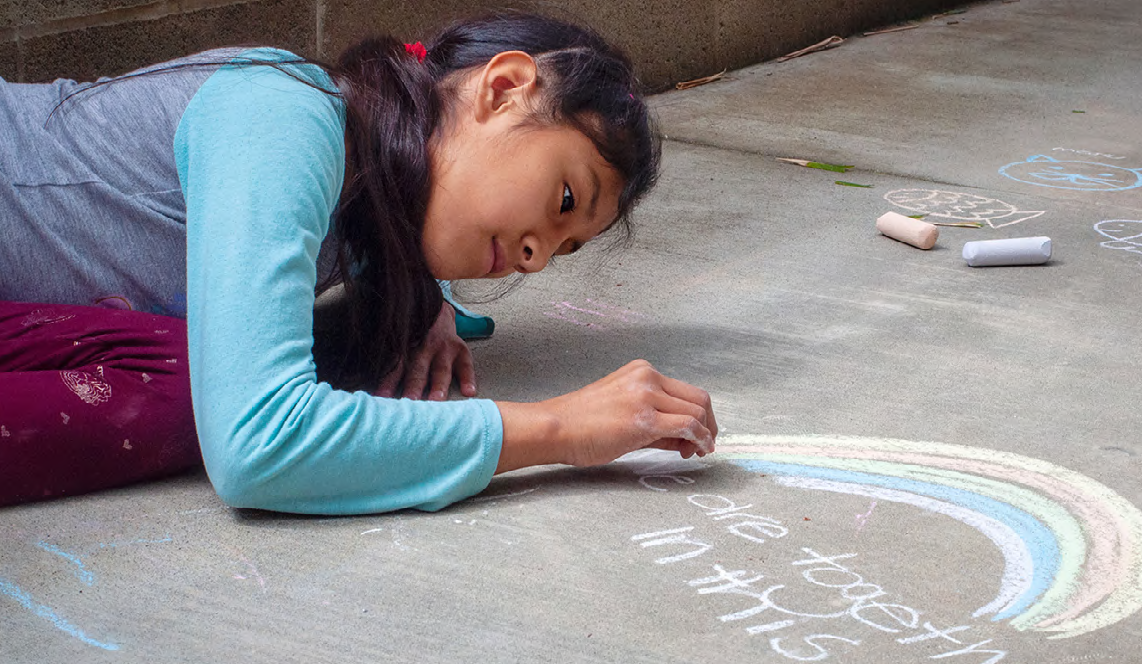 A young girl drawing with chalk on a sidewalk
