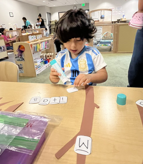 A young child making a name collage at the Family Support center