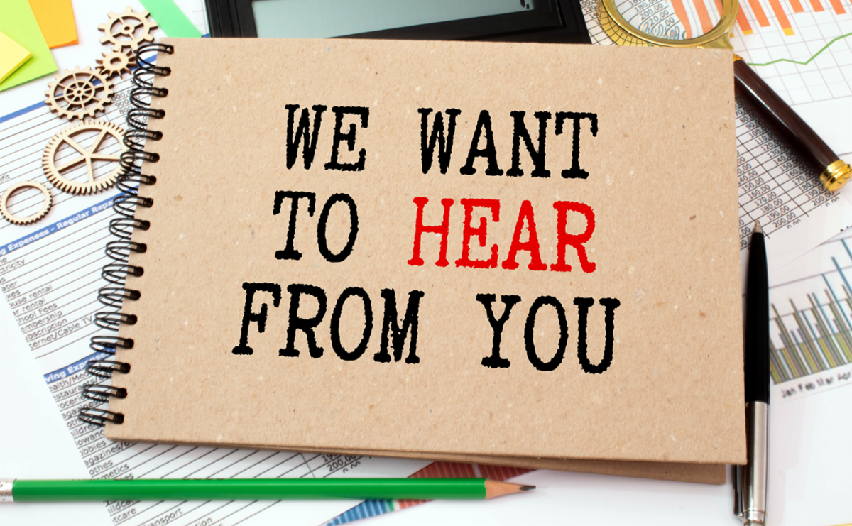 The words We want to hear from you printed on a spiral notebook