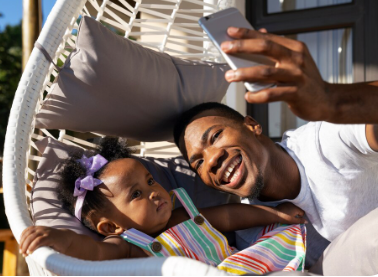 An African American dad and daughter looking at a cell phone