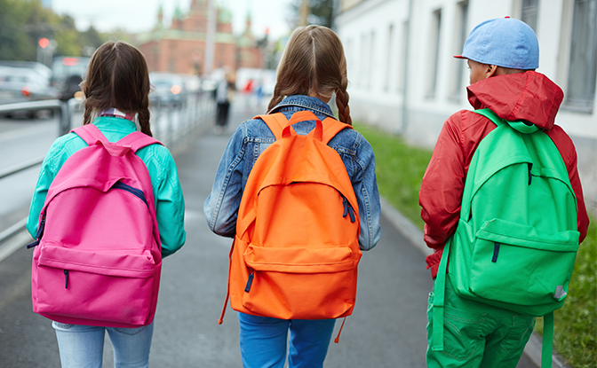 Three kids headed to school with backpacks on