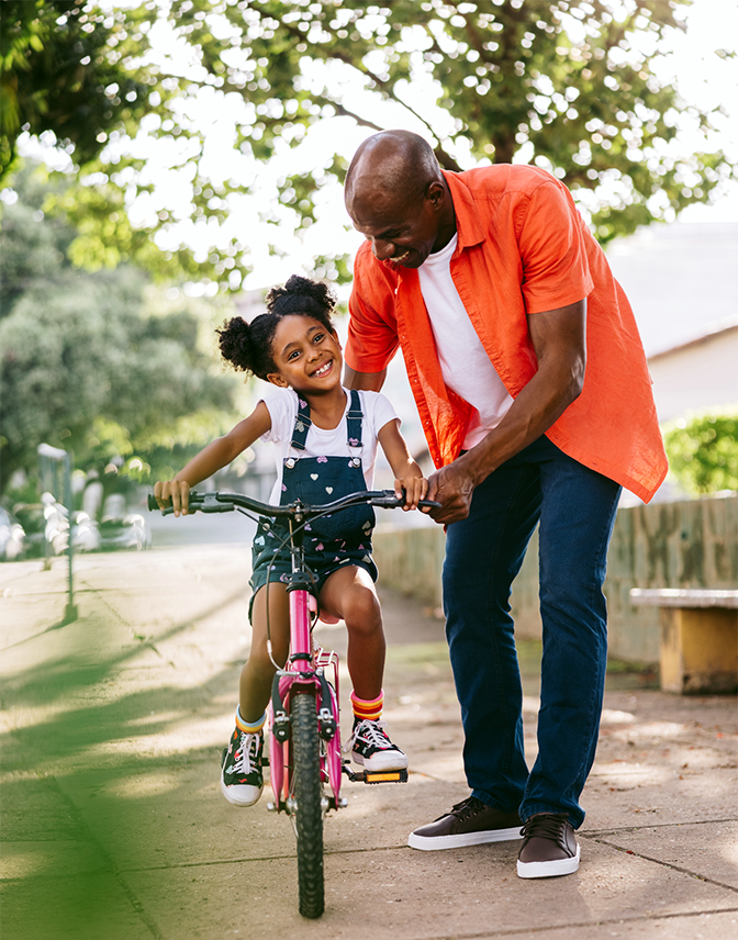 An African American dad teaching his daughter how to ride a bike