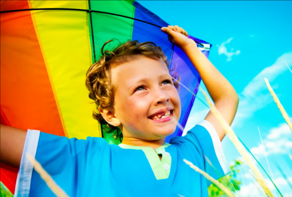 Young boy flying a colorful kite