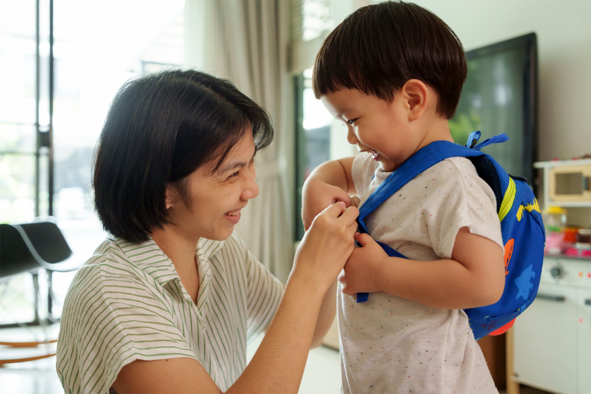 Asian mother helping her son get ready for kindergarten