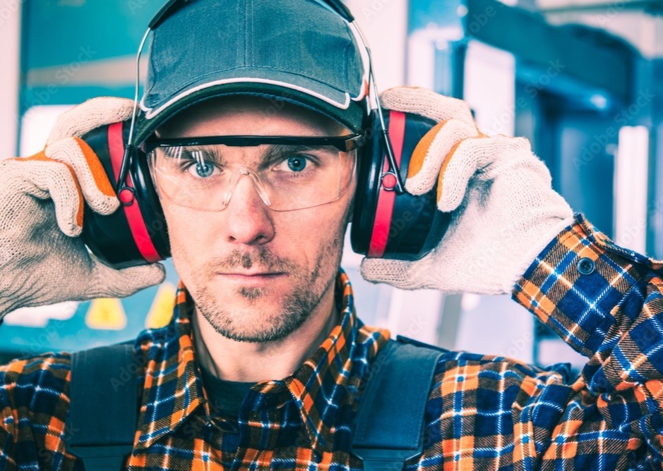 Man in industrial setting wearing hearing protection. 