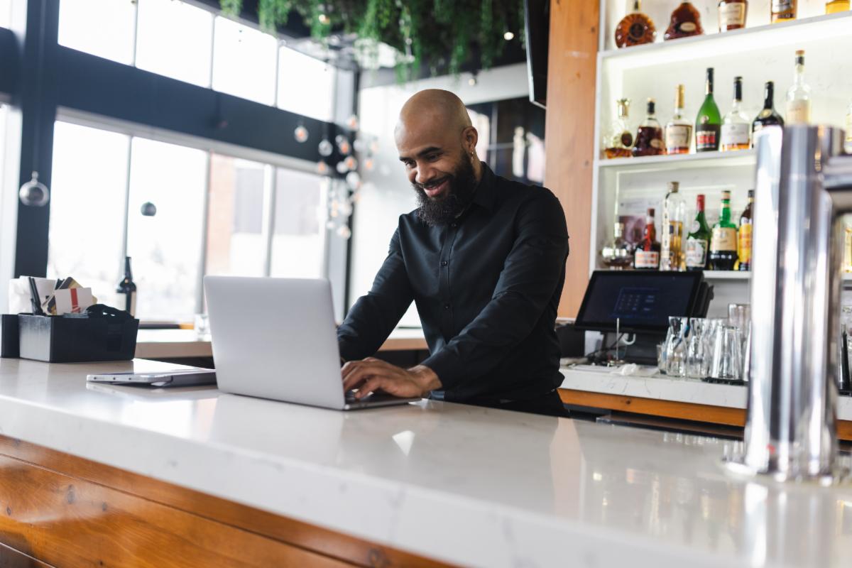 Cheerful Man Using Tablet at Work in His Bar