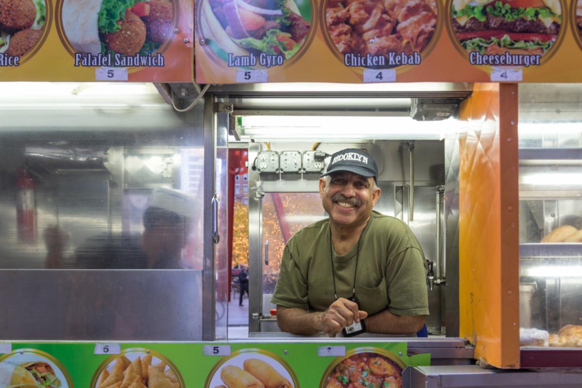 A happy street cart vendor looking out of his selling window