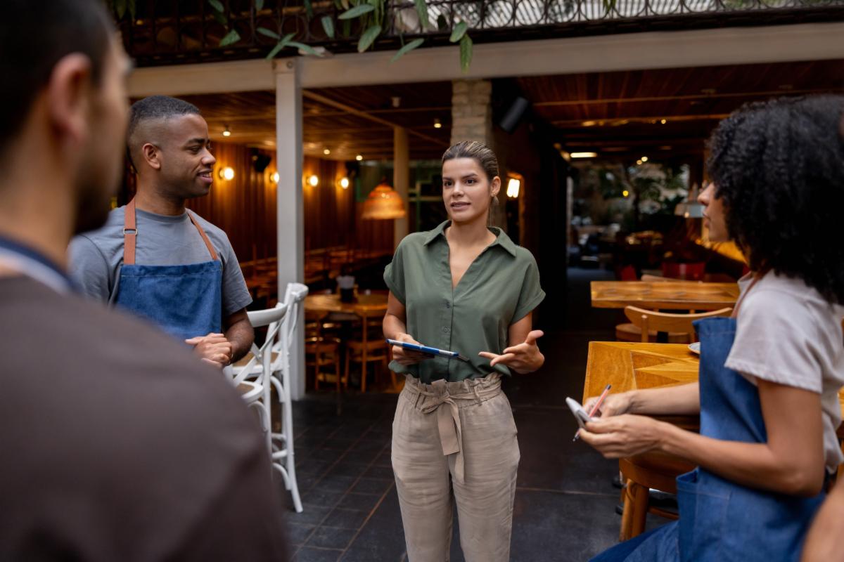 Latin American business manager talking to the wait staff in a meeting at a restaurant