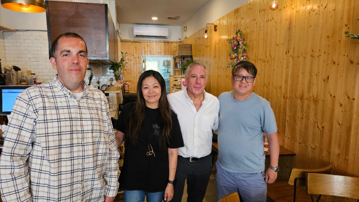 Four people standing together inside a cozy cafe with wooden walls and warm lighting