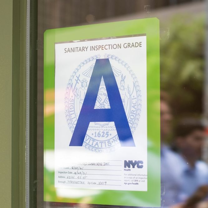 NYC Sanitary Inspection Grade sign hanging on a window of a food business