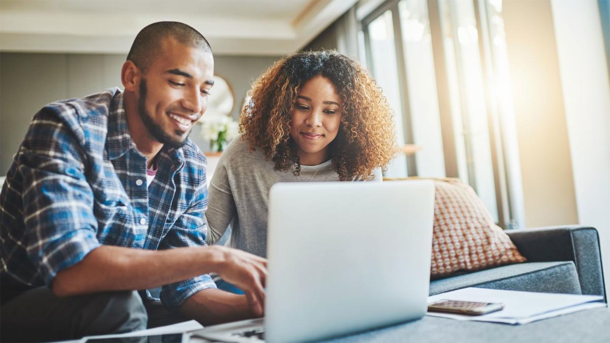 Two people look at a computer in a home