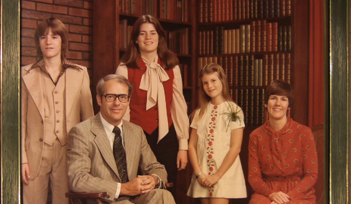 A framed traditional family photo from the 1970s with a spider crawling on top.