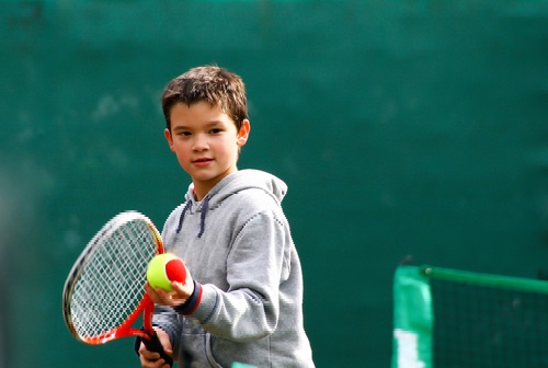 Little tennis player on a blurred green background