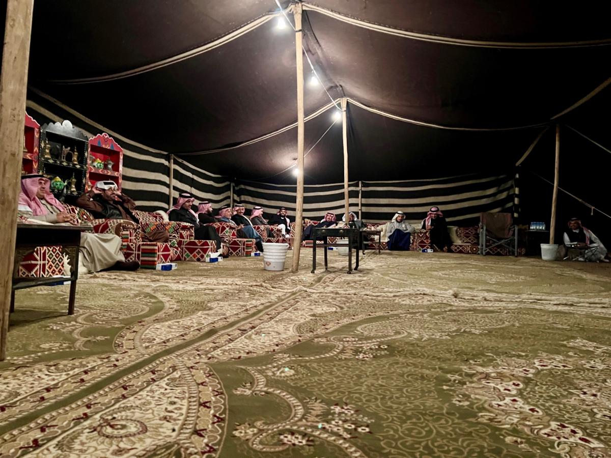 Individuals sit inside a large tent