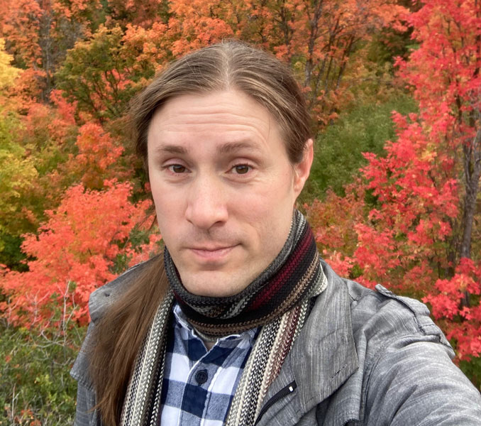 Shoulder's up photo of a person surrounded by fall foliage