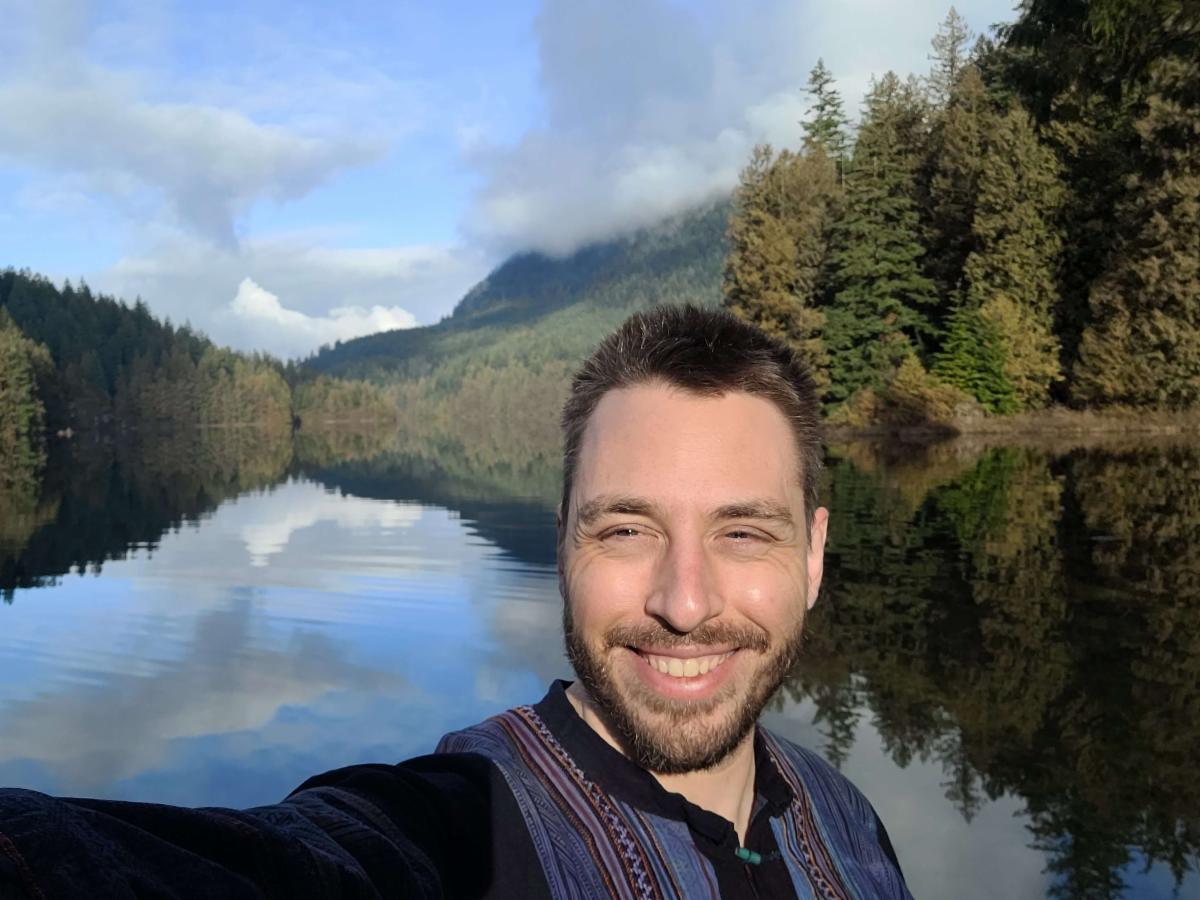 Selfie of Brandon Weigel by a lake. He is smiling at the camera.