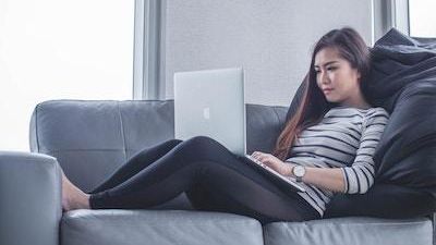 Woman on sofa working on laptop computer.