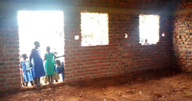 Students in Uganda stand outside a pre-renovated school room.