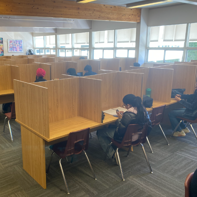 A view of study carrels in the library of Coquitlam College. Students sit at the study carrels doing work.