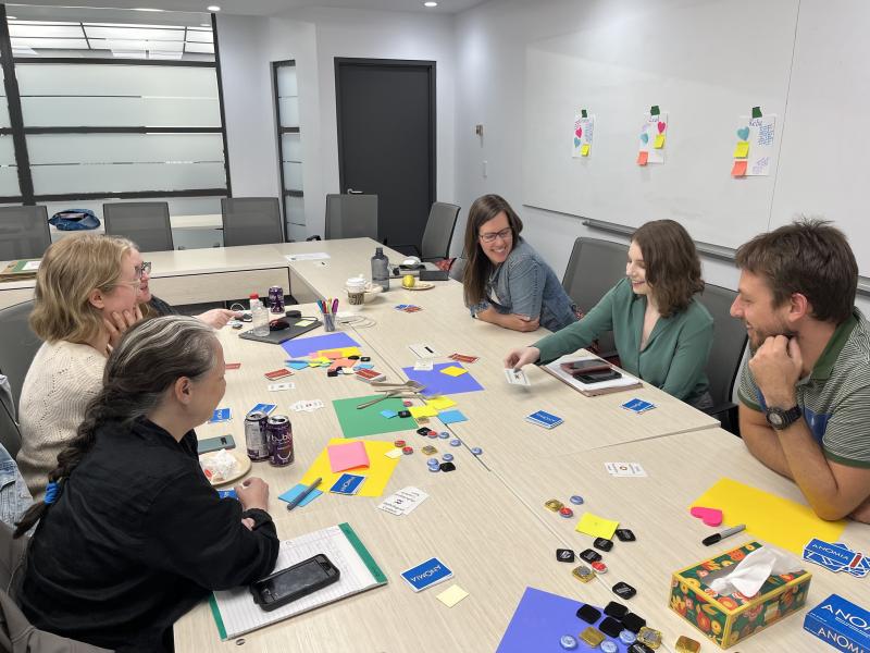 Five BC ELN staff members discussing and sketching ideas with paper and markers at a table.