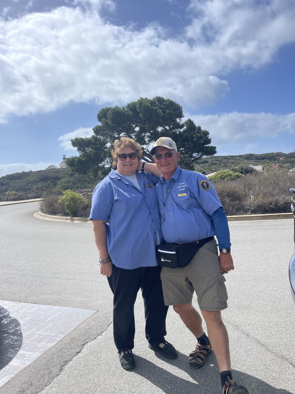 VIPs Jeannine and Rod pose at Visitor Center roundabout, showing off their new Cabrillo National Monument VIP fanny packs.