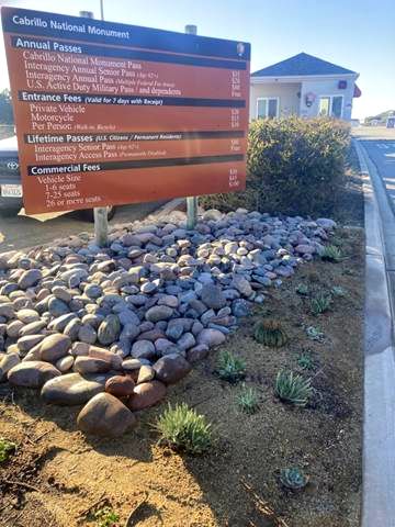 Photo of entrance station sign, which underneath has rocks and a patch with newly planted succulents and cacti. 