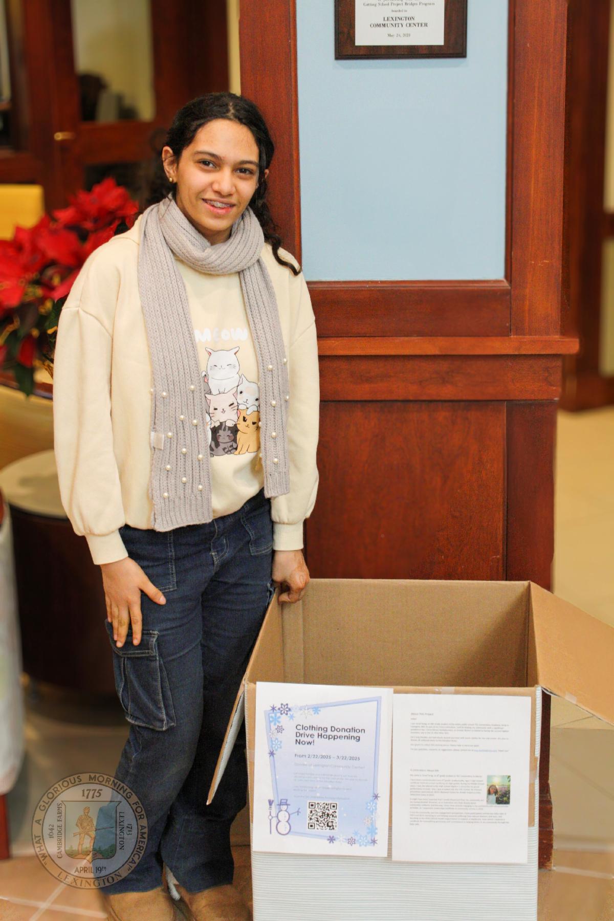 Ferial Farag standing with the donation box she place in the lobby of the Lexington Community Center