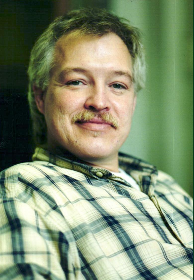 Portrait photograph of a man in a plaid shirt