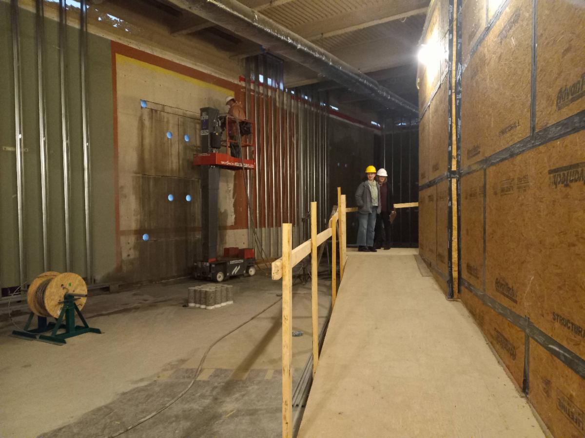 Large open building space with people wearing hard hats.