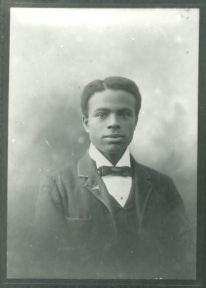 Black and white portrait photograph of a young African American man in a suit and bow tie.