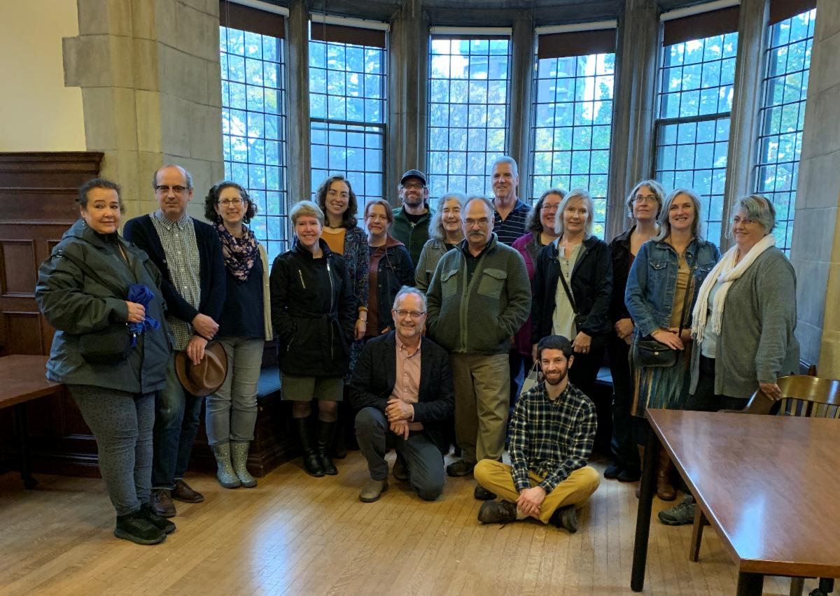 Group of people posed in a room with windows.