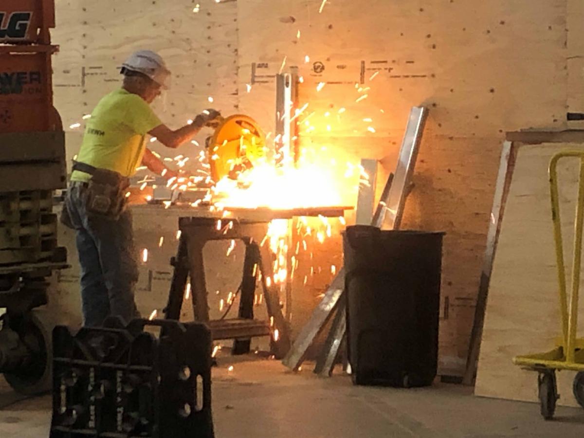 A sub-contractor cuts steel studs to support new drywall.