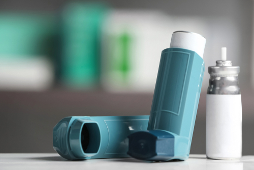 Asthma inhalers on table against blurred background. Space for text