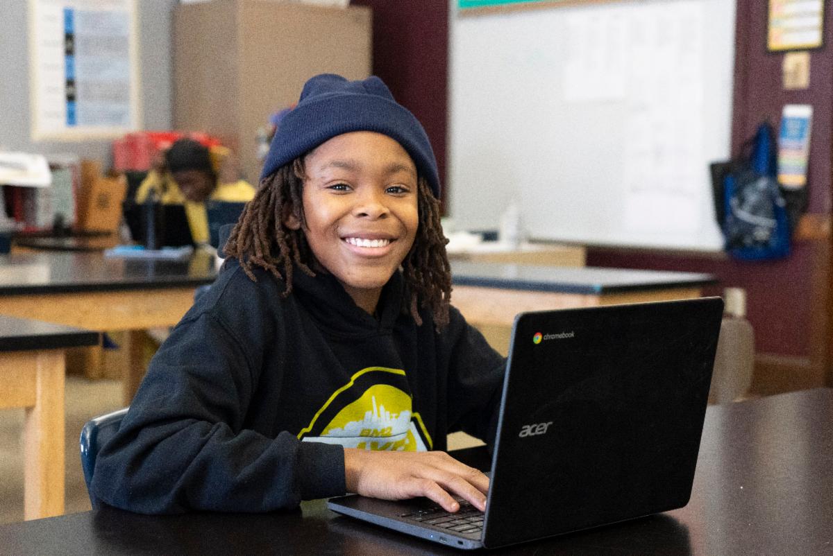 MPS student smiles while working at his Chromebook.