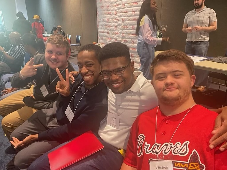 A group of four young men  from IDEAl program smiling two white and two black