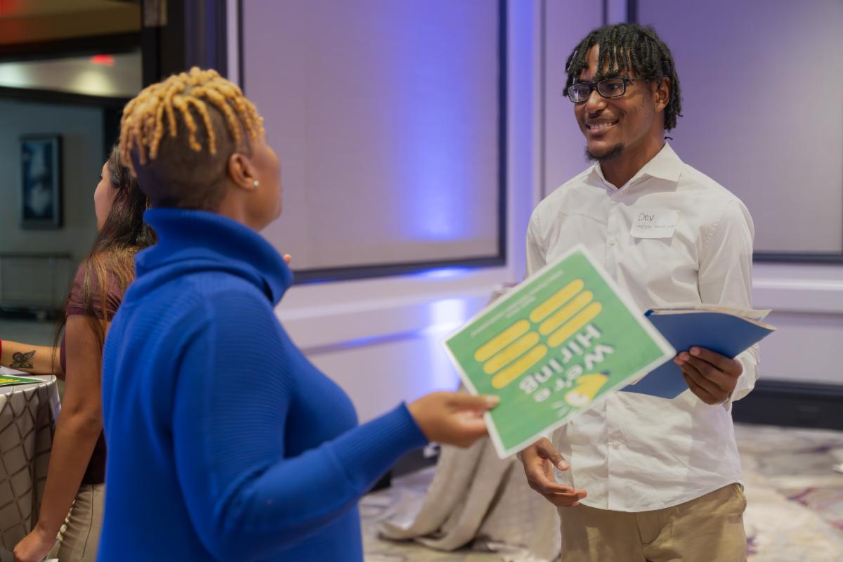 Black woman from career fair talking to young black man from IDEAL program