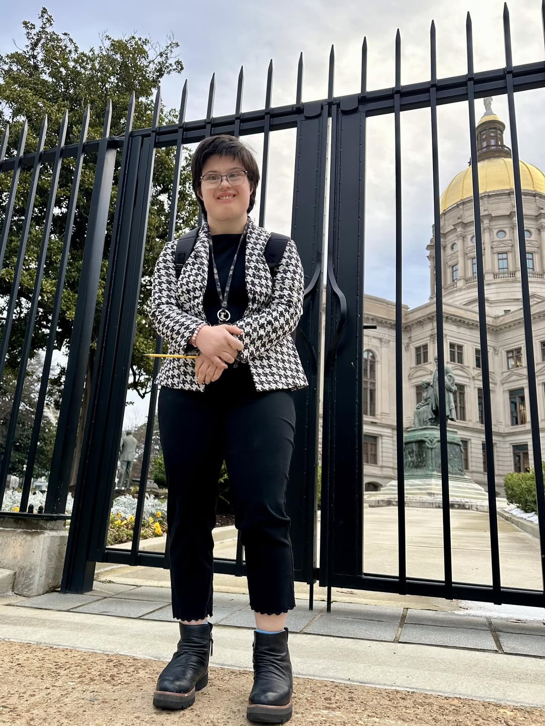 Young lady with down syndrome with glasses standing in front of Georgia Capitol