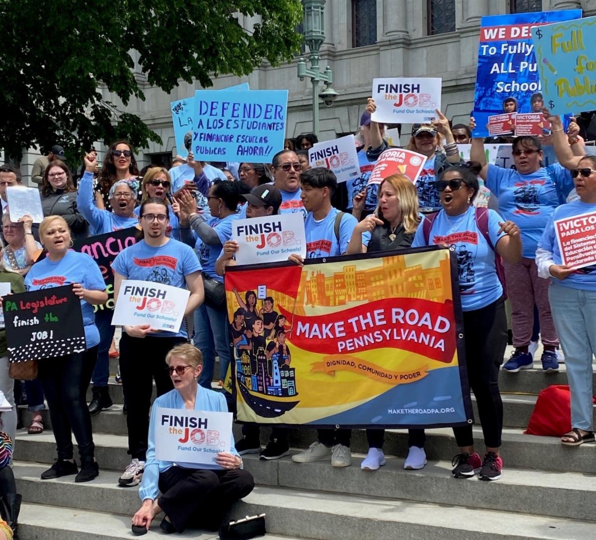 supporters of public schools hold colorful signs at a Harrisburg rally