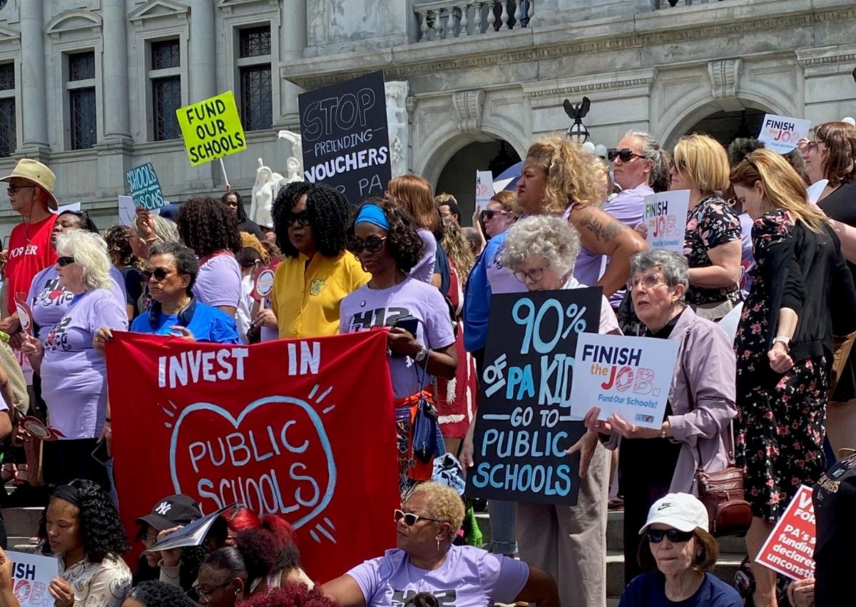 supporters of public schools hold colorful signs at a Harrisburg rally