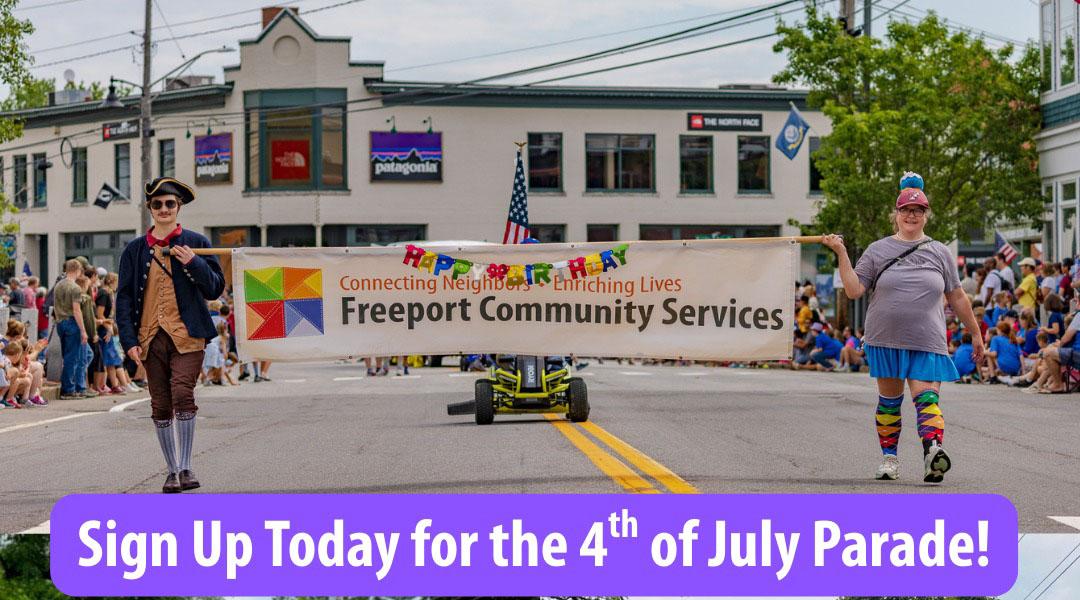 Parade in street with two smiling people holding a Freeport Community Services banner