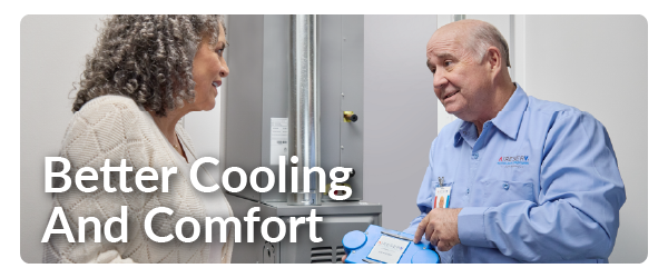 a man in a blue Aire Serv shirt explaining air conditioning to a woman in a white sweater