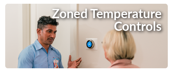 a man in a blue Aire Serv shirt explaining an AC control panel to a blonde woman 