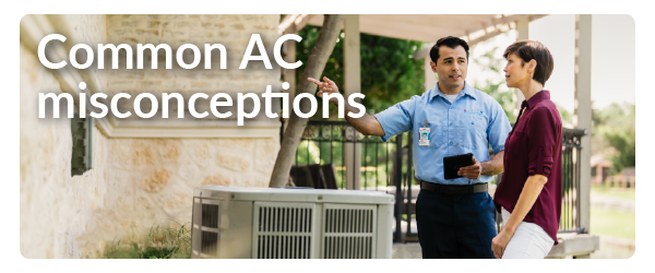 a man in a repairman's uniform showing an AC unit to a female in a purple shirt