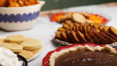 A spread of holiday pies and treats on a white table.