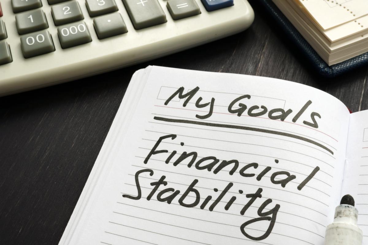 Notebook page with handwritten “My Goals: Financial Stability” next to a calculator.